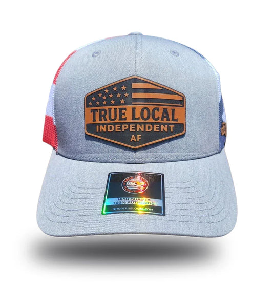 Gray True Local trucker hat with patriotic patch, red-white-blue mesh, and authenticity tag for Florida pride apparel.
