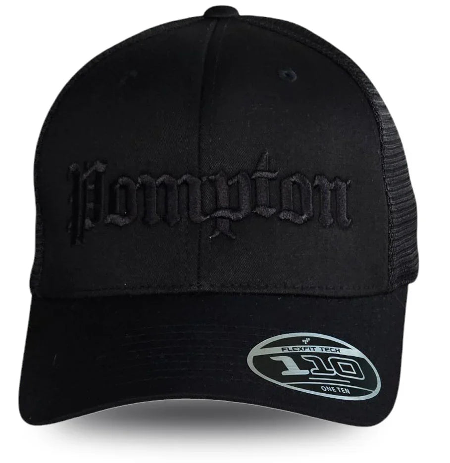 Black Pompton trucker hat with embroidered gothic lettering, mesh back, and Flexfit 110 label