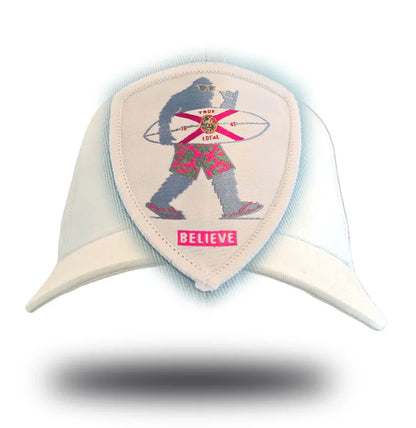 White cap with embroidered Bigfoot holding surfboard, Florida flag, 'BELIEVE' patch — local Florida pride apparel