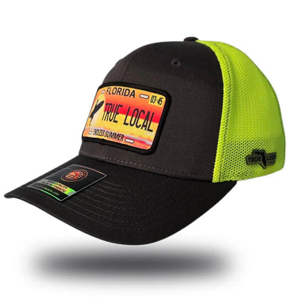 Black and neon green trucker hat with Florida 'True Local' license plate patch, celebrating endless summer vibes.